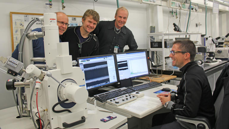 HSN-nøkkelpersoner samlet rundt elektronmikroskopet.