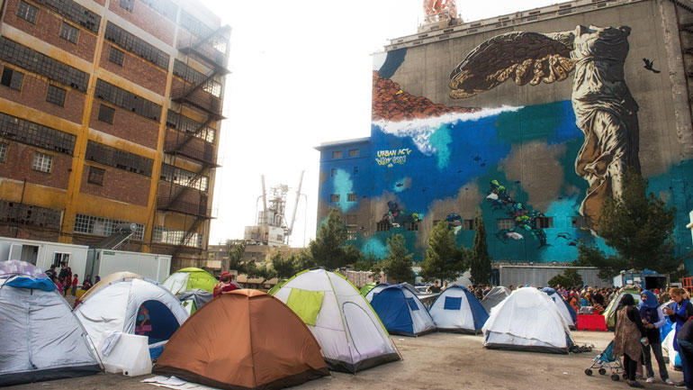  Flyktninger fra krigen i Syria blant bygninger og veggmalerier ved havnen i  Pireus ved Athen. Foto: iStock/AshleyWiley