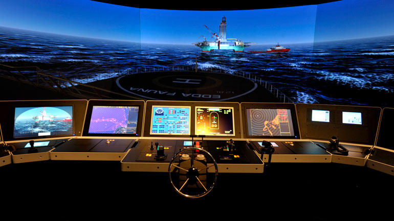 Maritim simulator illustrasjon som viser står 360 graders skjerm med skip og oljerigg utpå havet og mange små dataskjermer og tastatur og ratt. 