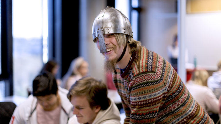 Lektorstudent i historie står i et klasserom med en vikinghjelm