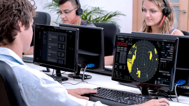 Studenter en jente og to gutter i klasserom foran PC-skjermer med skybasert simulatortrening