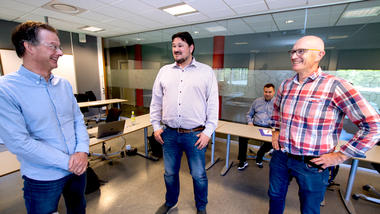 Tor Erik Jensen (til venstre), prosjektleder Christian Hovden og universitetslektor Paul Nikolai Smit stående på rekke i møterommet og ser på hverandre og smiler. 