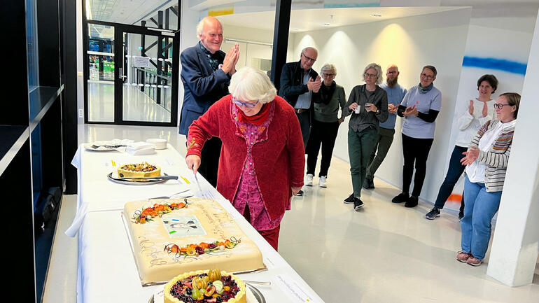 JUBILEUMSKAKE: Anna Sethnes oldebarn Janne Wilberg fikk æren av å ta det første kakestykket. I bakrunnen professor emeritus Willy Aagre som applauderer. (Foto: Jan-Henrik Kulberg / USN)