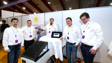 De fem ingeniørstudentene i hvite like skjorter på stand under regionmesterskapet for studentbedrifter og viser frem solcellepanel/testplater