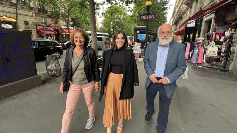 Viserektor Ingvild M. Larsen, studentleiar Nora R. Houidi og rektor Petter Aasen går ved siden av kvarandre på ei gate i Paris. Dei ser i kamera og smiler.