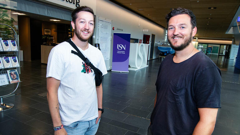 Halvportrett av brødrene Stian og Andreas utenfor servicetorget på campus Vestfold, smiler til kamera.  
