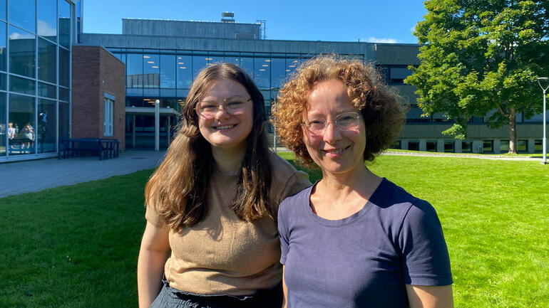 Linea Ødegård og Amber Struijk står ute i sola foran campus Porsgrunn og ser i kamera og smiler