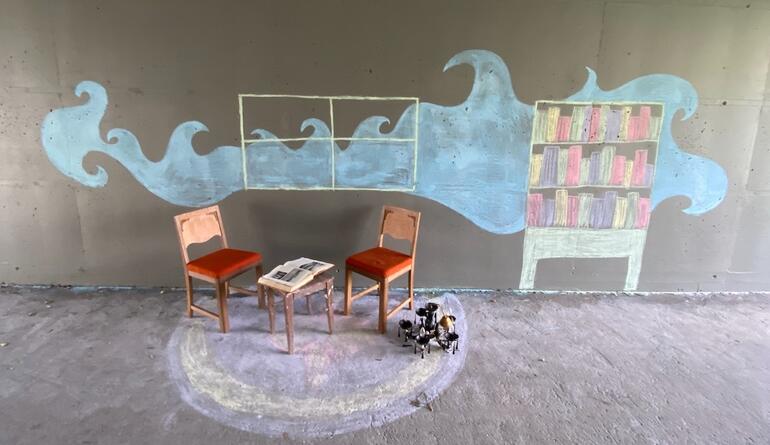 Empty chairs and table in front of concrete wall with chalk graffiti