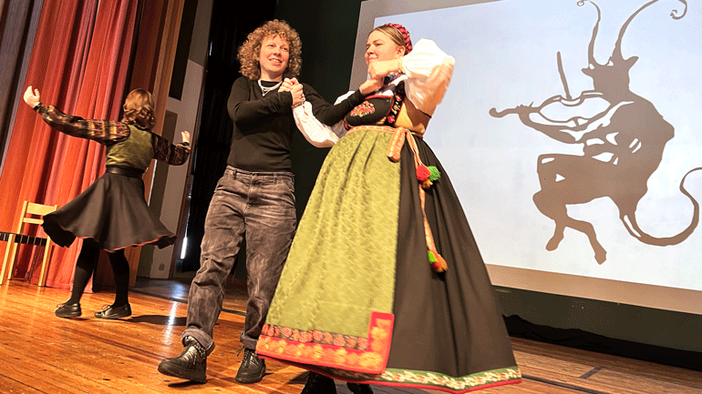 Tuva Syvertsen danser på ei scene med Vintefestivalen på Rauland sin logo i bakgrunnen. Foto