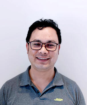 Portrett av Ashish Shrestha med sort hår og sorte briller og grå piquet-t-skjorte